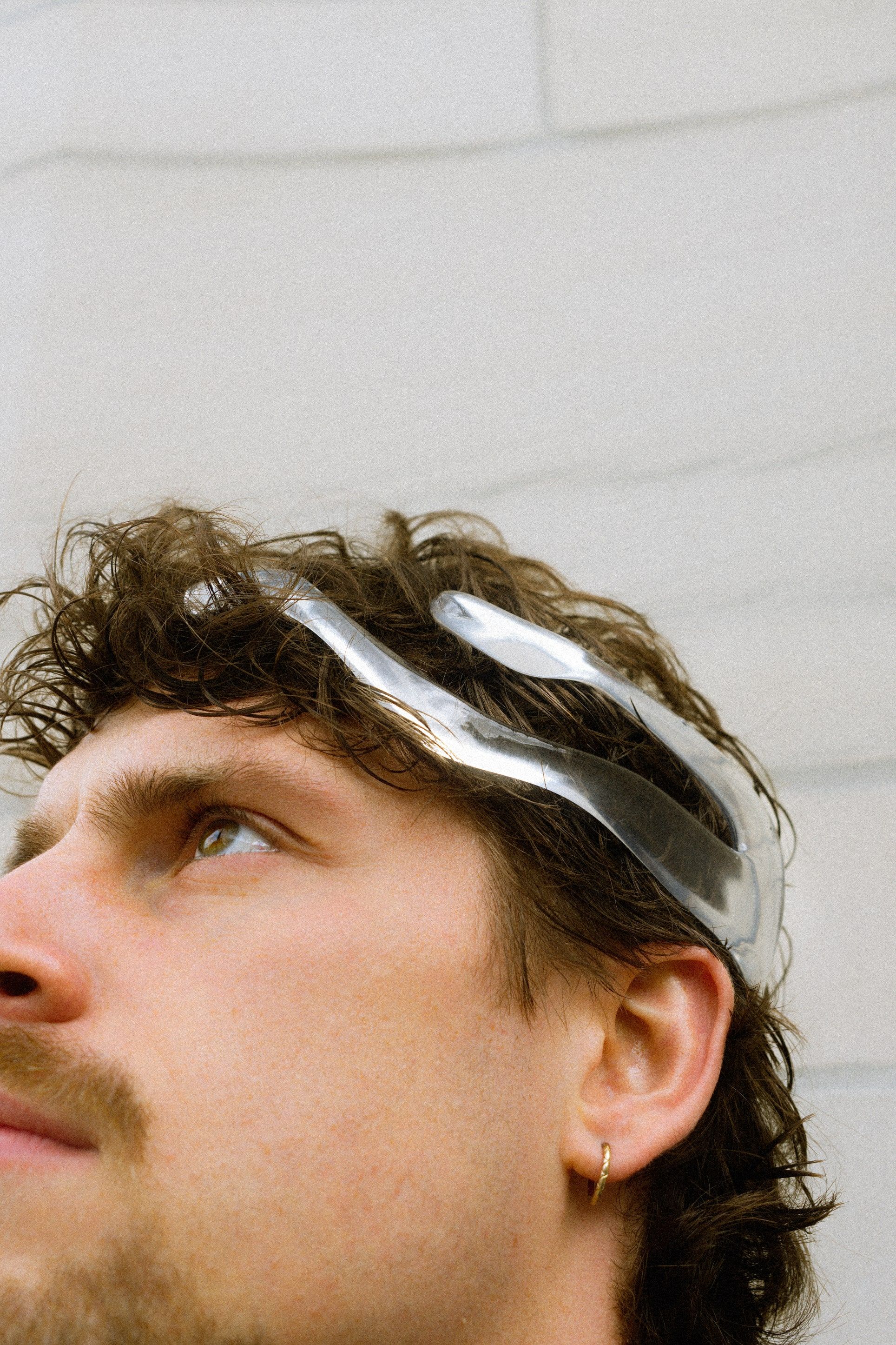 A man looking up, wearing the transparent Mourning Crown neurodevice