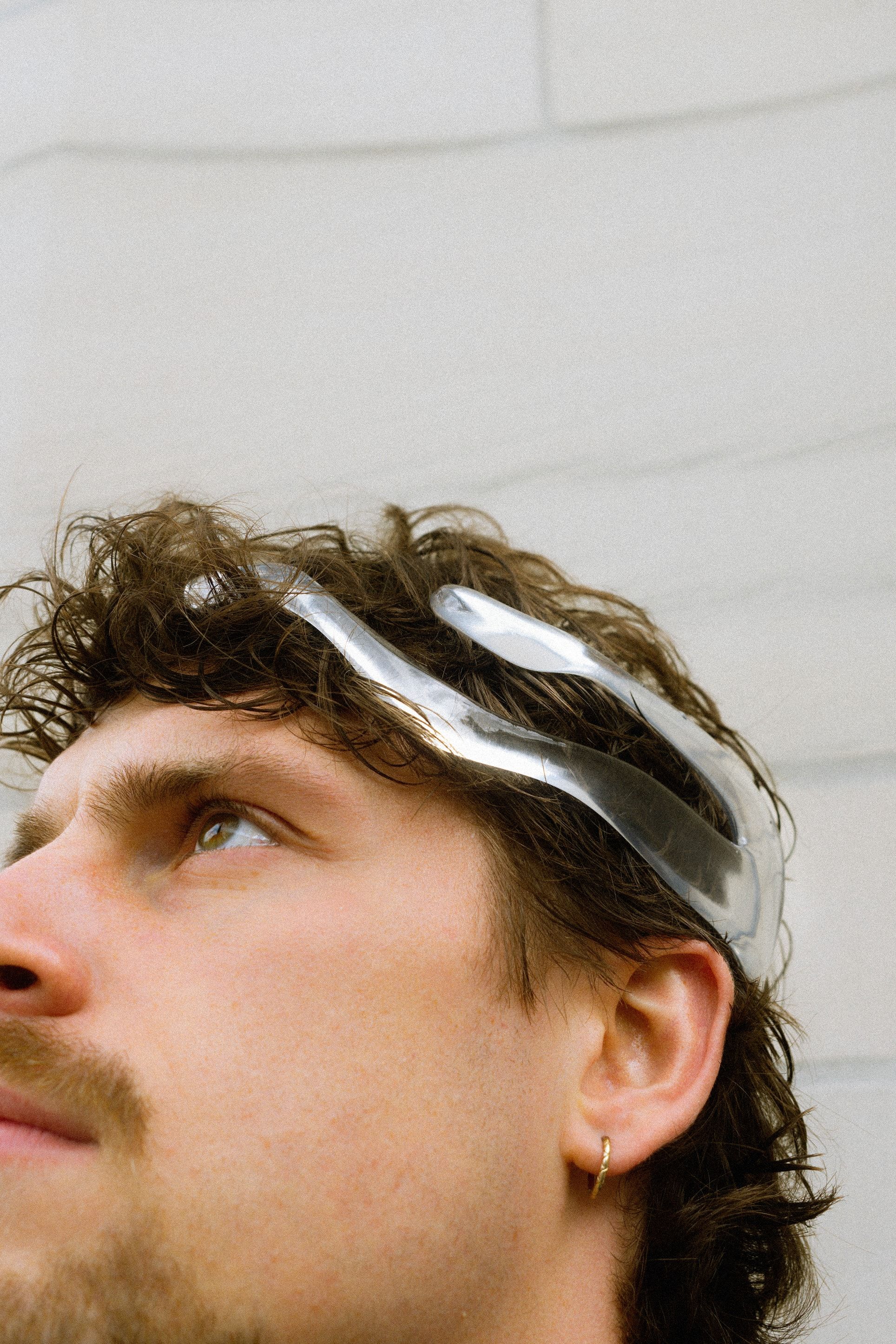 A man looking up, wearing the transparent Mourning Crown neurodevice