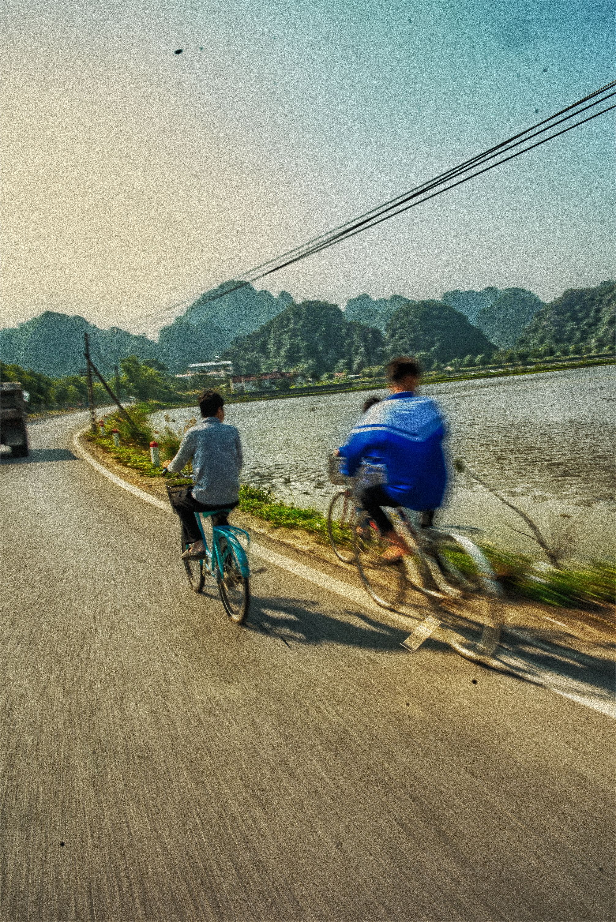 Vietnam — cyclists on a road by the rice paddies
